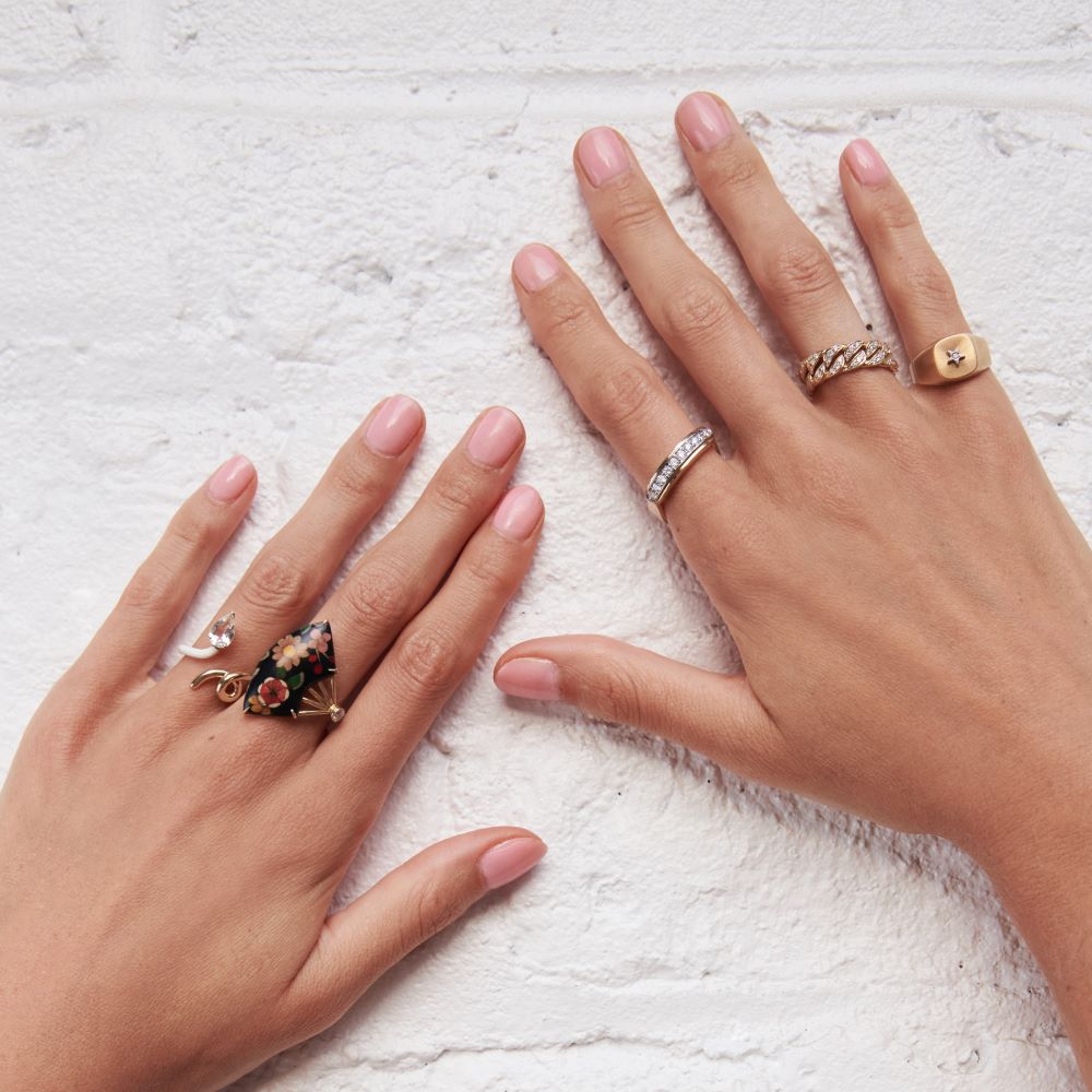 A woman's hands adorned with an Anna Maccieri Rossi diamond ring and an Anna Maccieri Rossi yellow gold Ora Gold Cushion Ring featuring a satin finish.