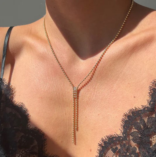 A woman is wearing a Vice Versa Gemini Bolo Necklace with a diamond tassel.