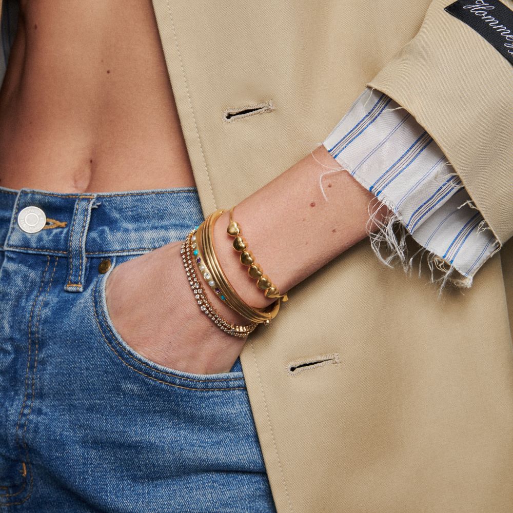 A woman wearing a yellow gold trench coat and Ondyn Rainsun Tennis Bracelets.