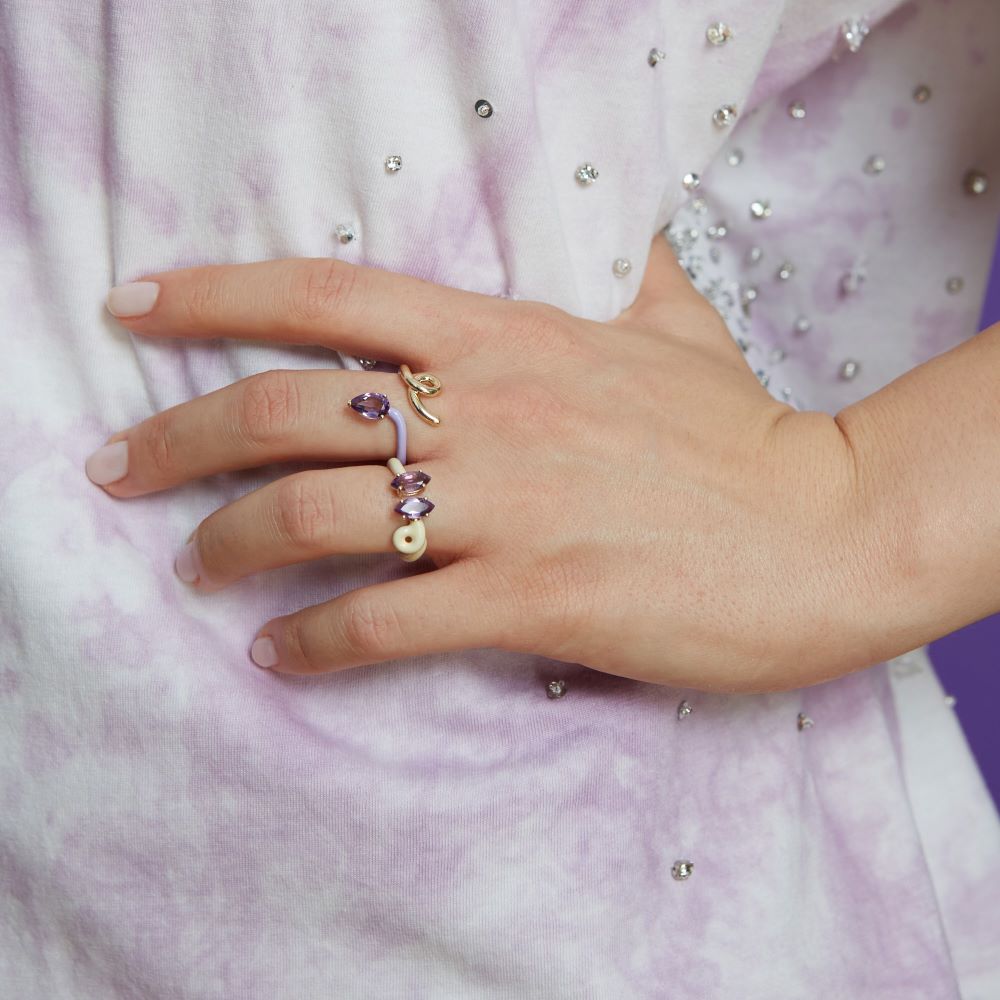 A woman wearing a purple tie-dye shirt and a yellow gold Bea Bongiasca Double B Ring Panna and Amethyst.