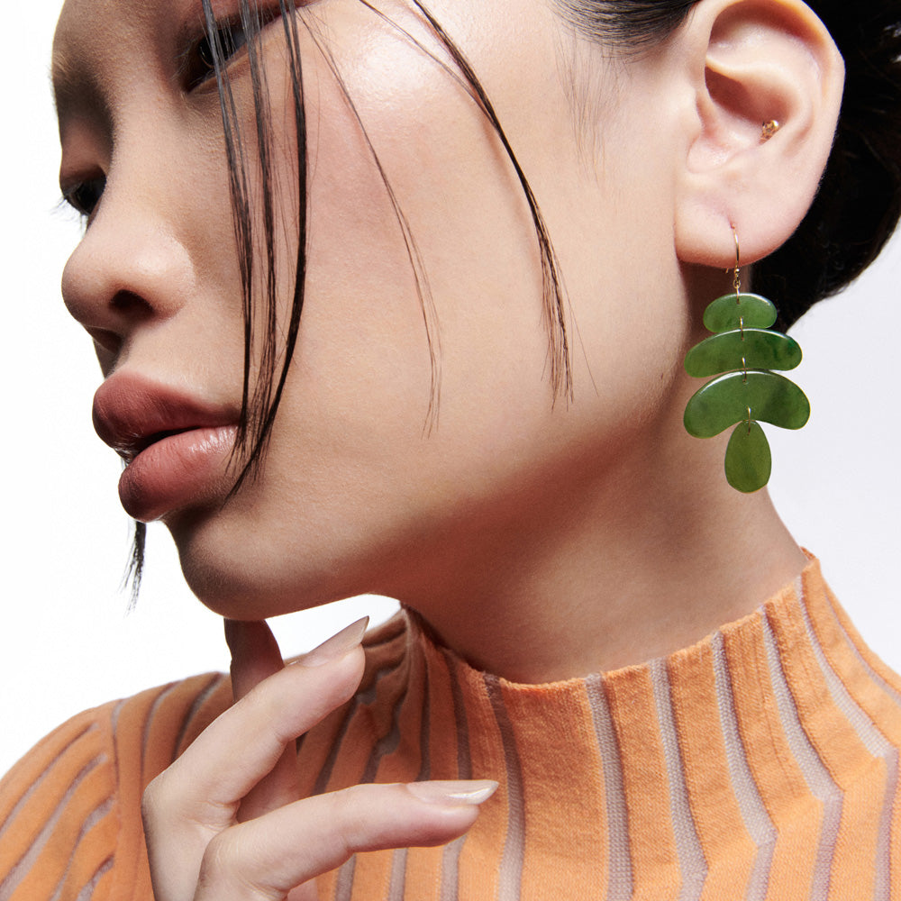 A woman is posing with Ten Thousand Things jade stone totem earrings.