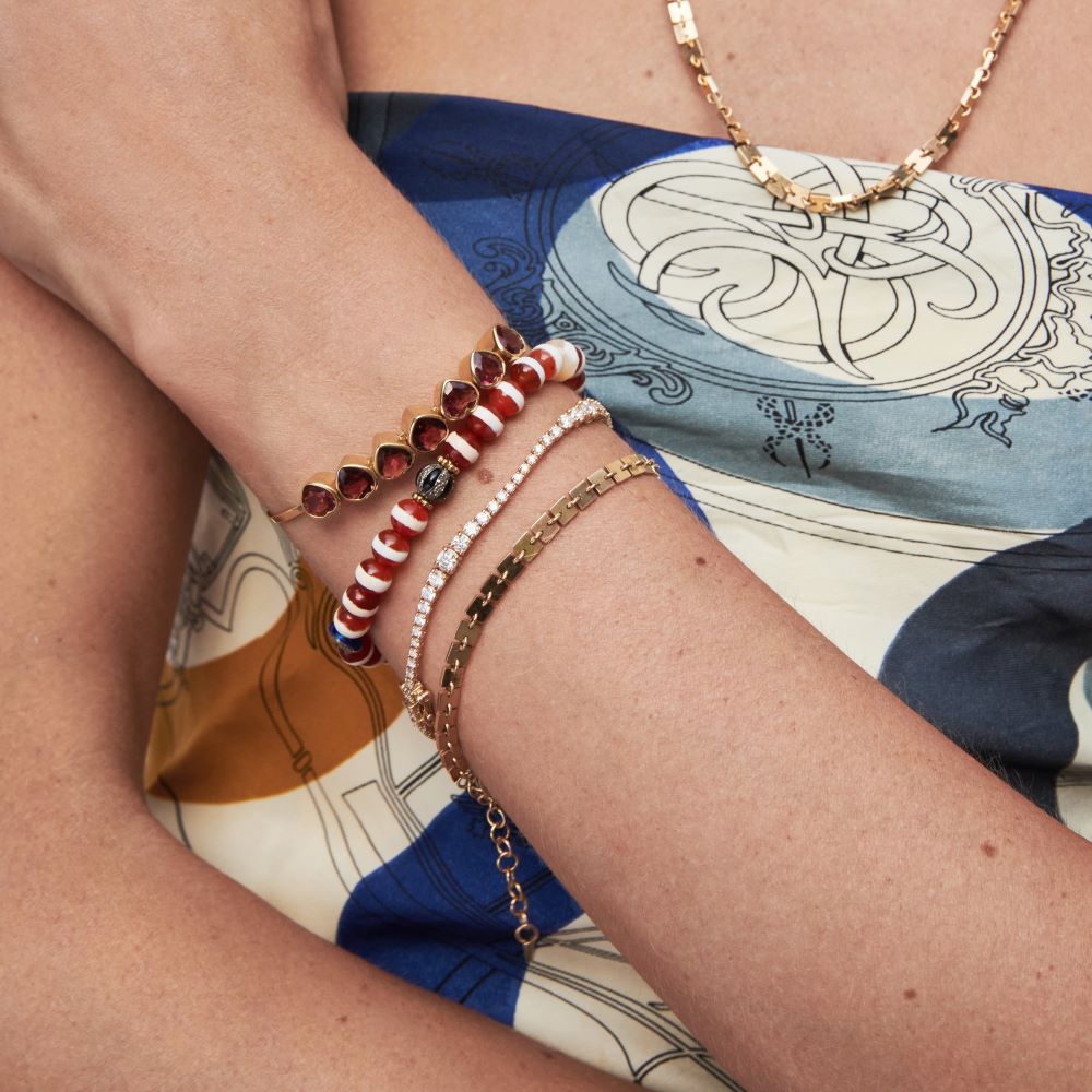 A woman wearing a yellow gold dress and Cadar Foundation Square Chain Bracelets with an adjustable length.