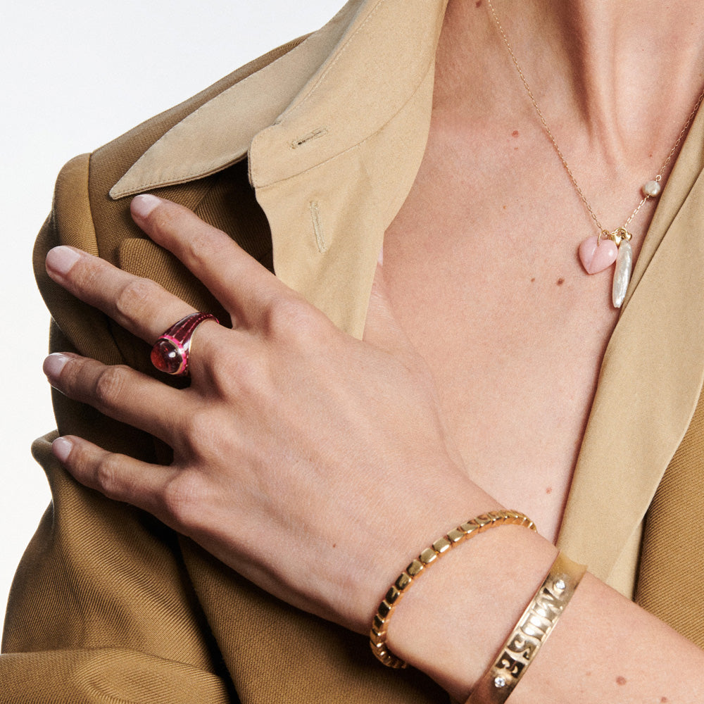 A woman wearing a tan jacket and a pink Orb ring with a yellow gold setting from KWIT.