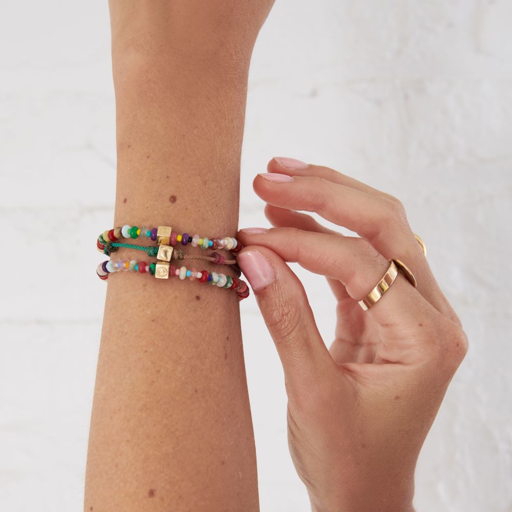 A woman is holding a Luis Morais Multi-stone cube Bracelet with charm.