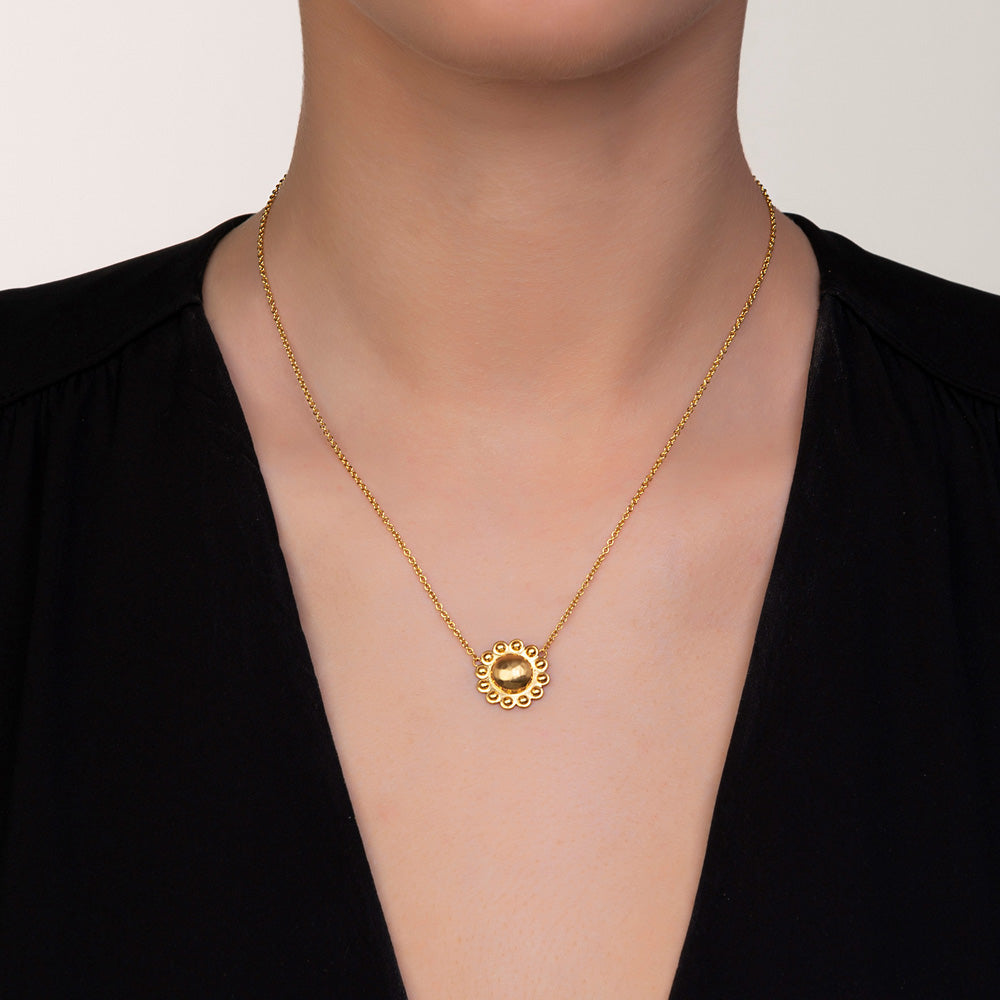 A woman wearing a Christina Alexiou Circle Flower Necklace with an adjustable length chain and a flower pendant.