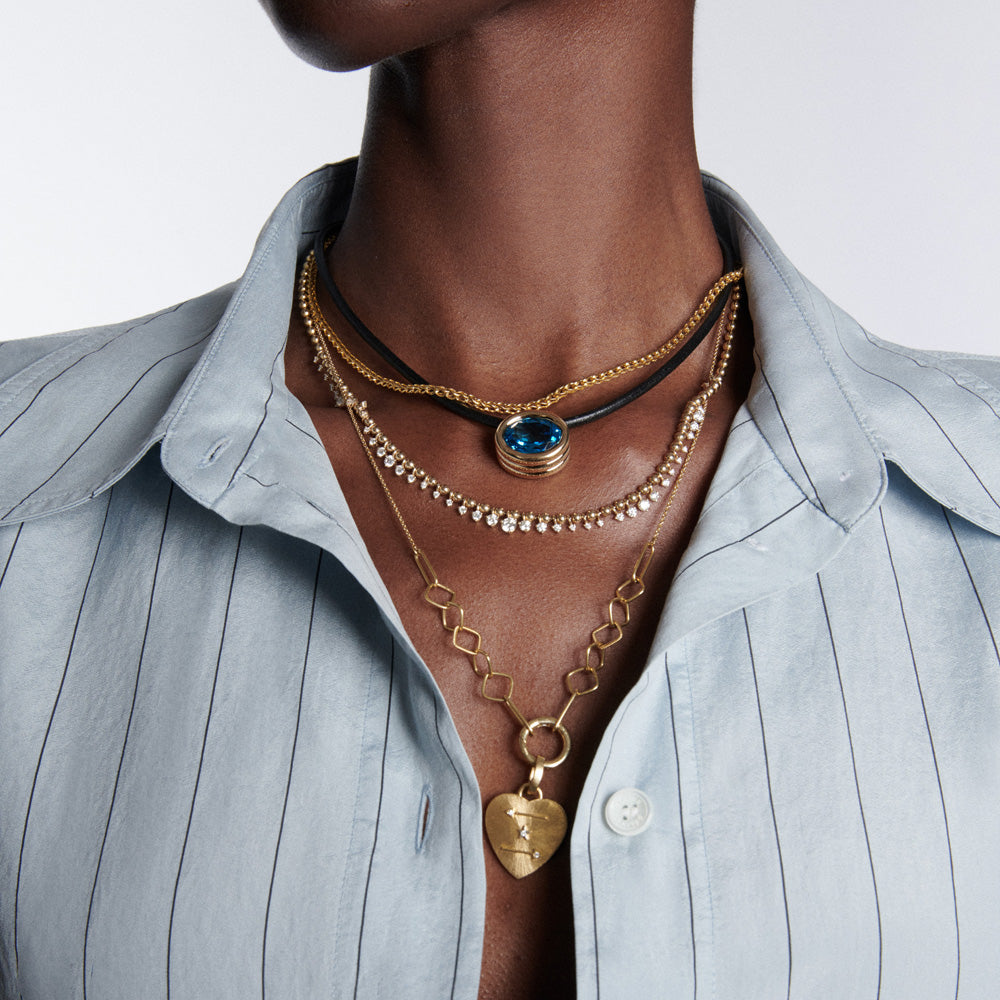 A woman wearing a blue shirt and gold necklaces, including a Beck Scuba Choker Necklace.