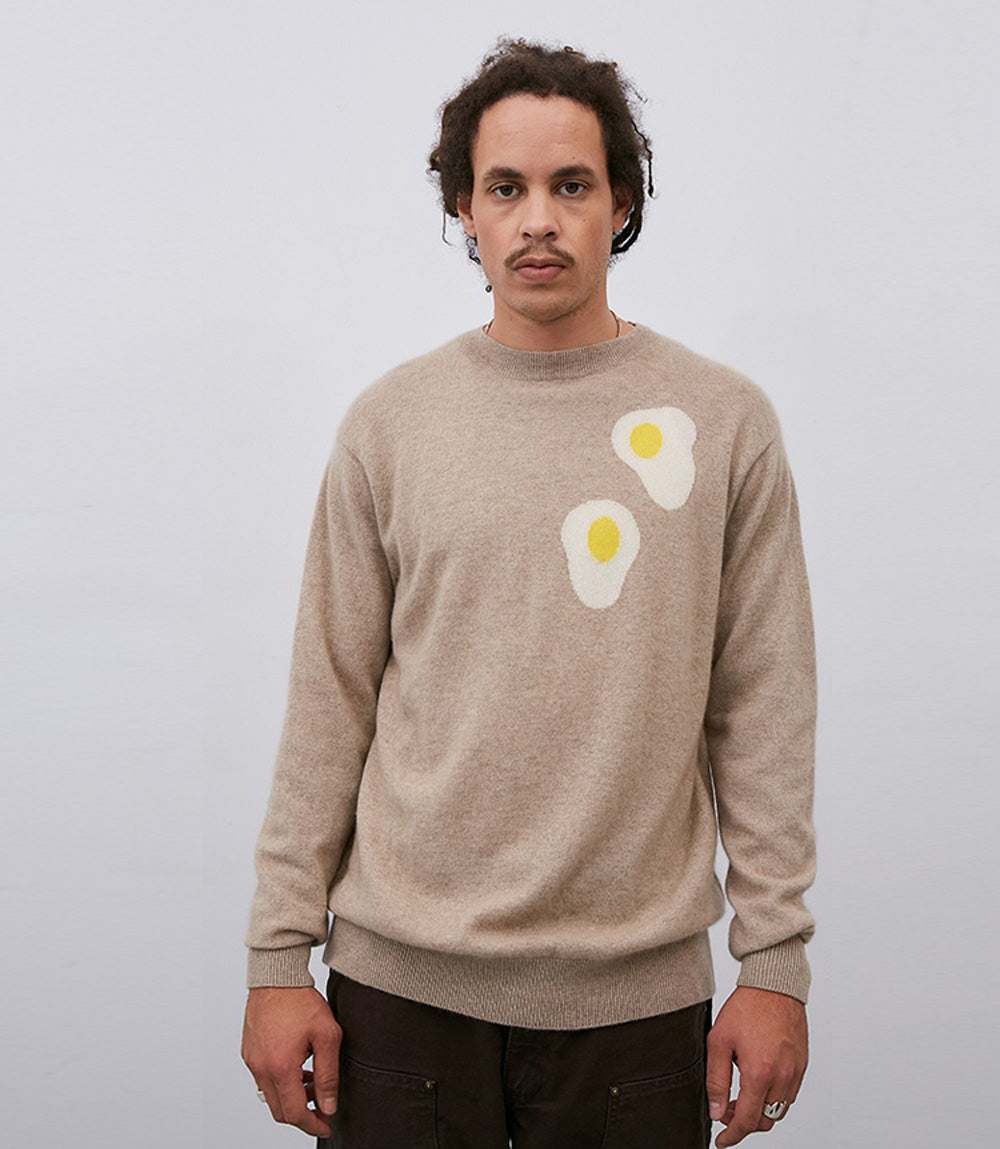 A man wearing a Leret Leret No. 62 Egg Sweater made of Mongolian cashmere with an egg on it.