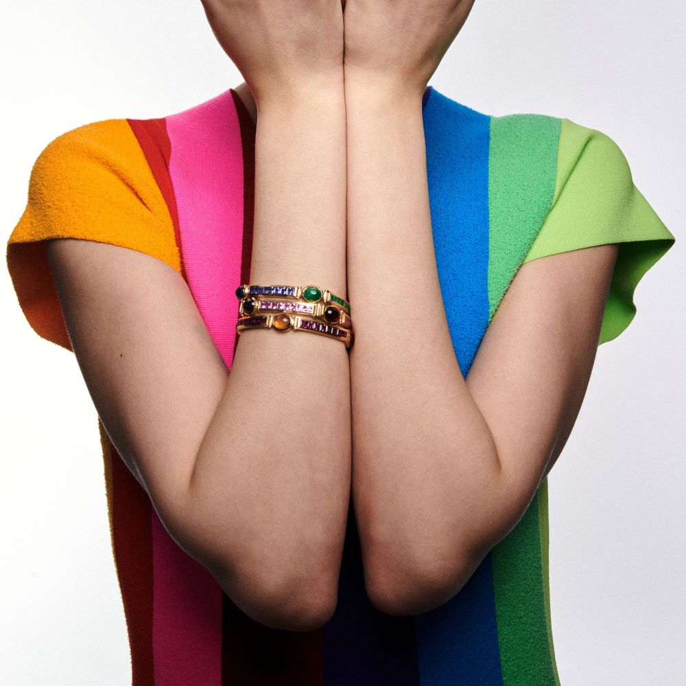 A woman in a colorful dress with her hands covering her face, wearing a VAN Stack Bracelet.