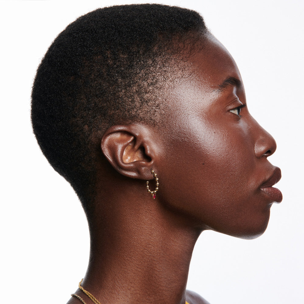 A black woman with a shaved head wearing Vice Versa's Kin Drop Earrings Ruby.