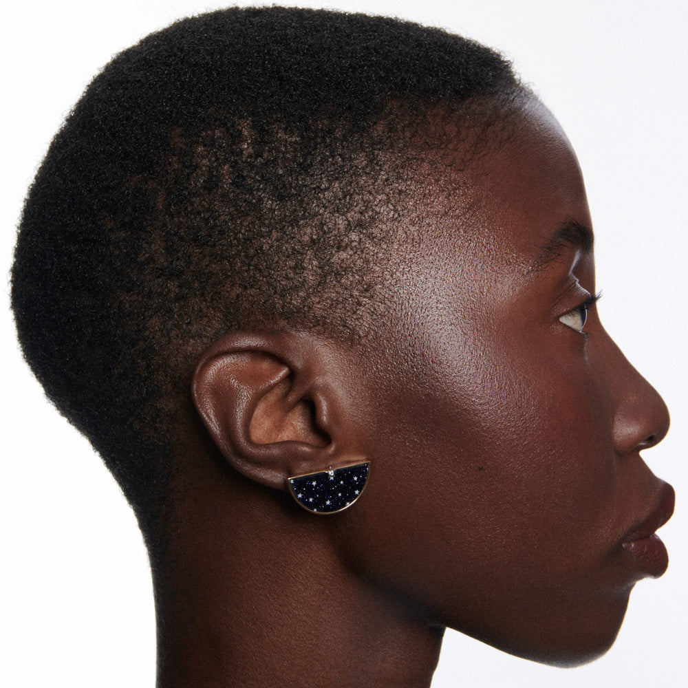 A black woman with short hair wearing a pair of Anna Maccieri Rossi Ora Half an Hour diamond earrings.