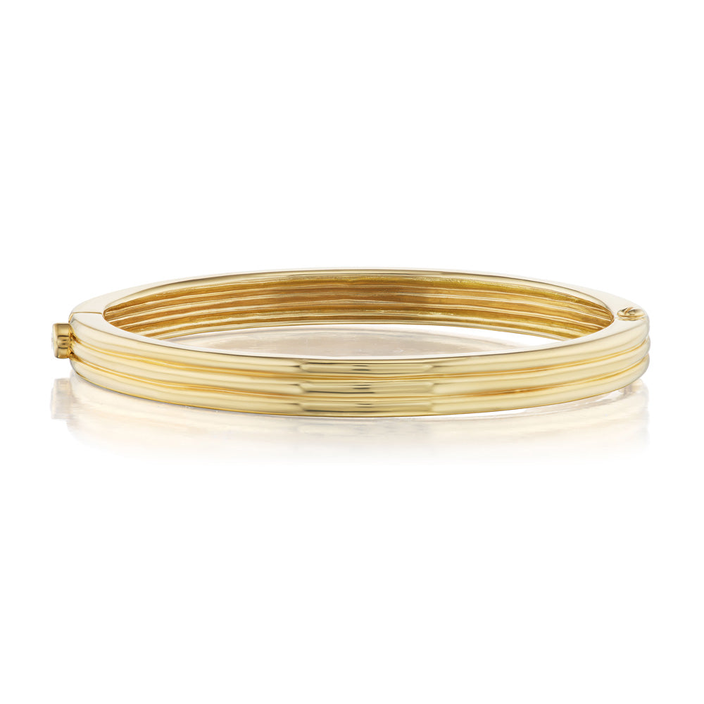 A yellow gold Scuba Trio Bangle by Beck on a white background, adorned with a precious stone.