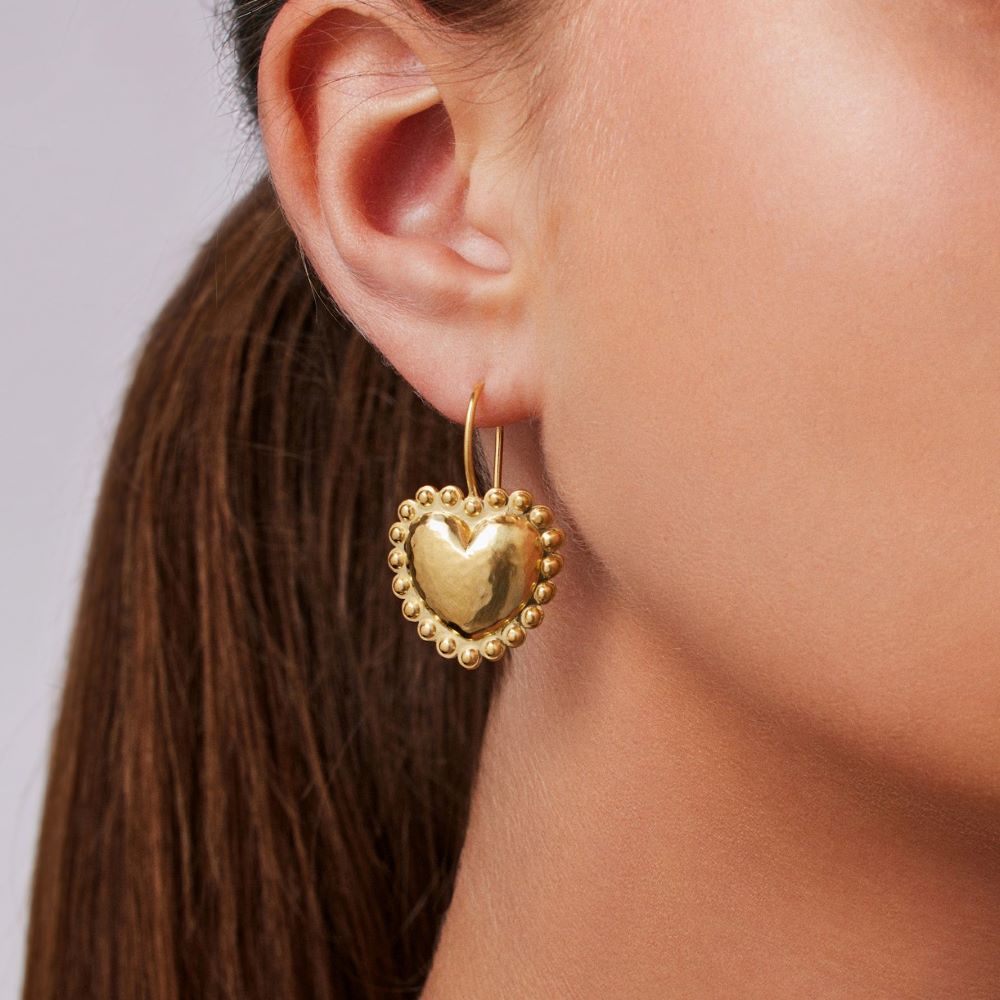 A woman wearing Christina Alexiou Circle Heart Wire Earrings made of 18k yellow gold.