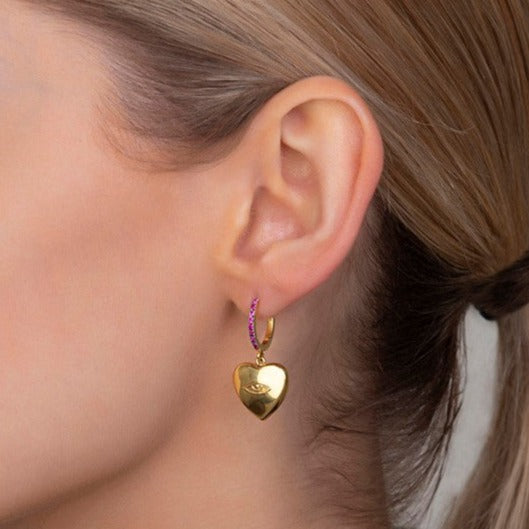 A woman wearing Christina Alexiou Protective Eye Heart Earrings.