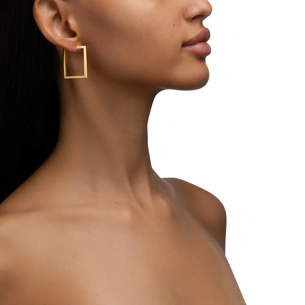 The model is wearing a pair of large Cadar 18k yellow gold square earrings.
