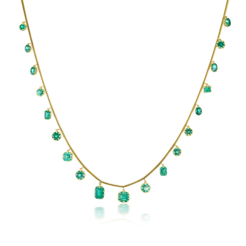 A Fringe Necklace Emerald by Jenna Blake with emerald stones on a yellow gold chain.