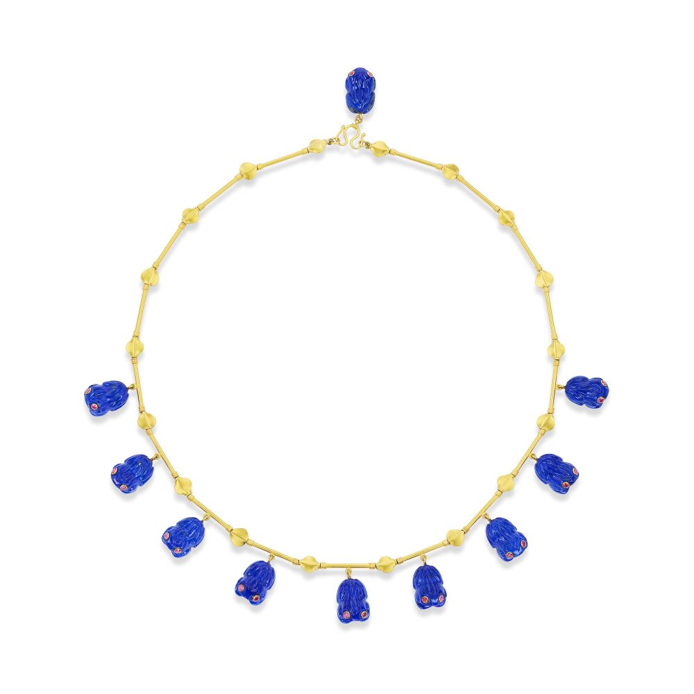 A Lapis Frog Necklace by Munnu, with lapis and blue beads and featuring hand-carved lapis frogs with ruby eyes.