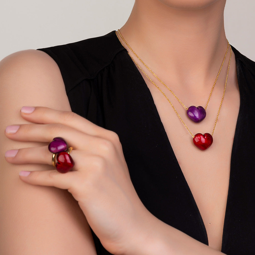 A woman wearing a red and purple Puffy Heart Necklace and Christina Alexiou rounded Puffy Heart Ring.