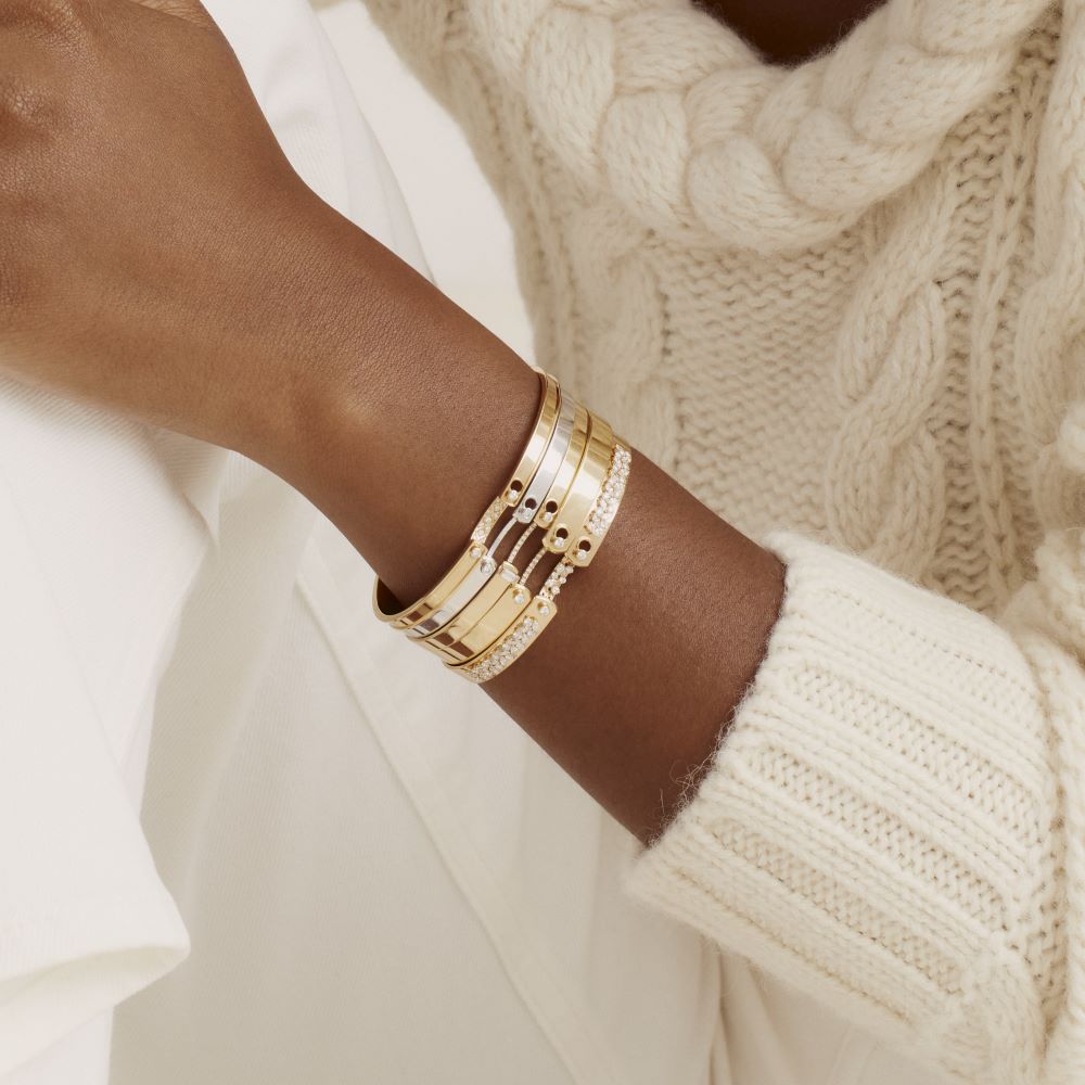 A woman wearing a white sweater and Nouvel Heritage Parisian Stroll Mood Bangle bracelets with round diamonds.