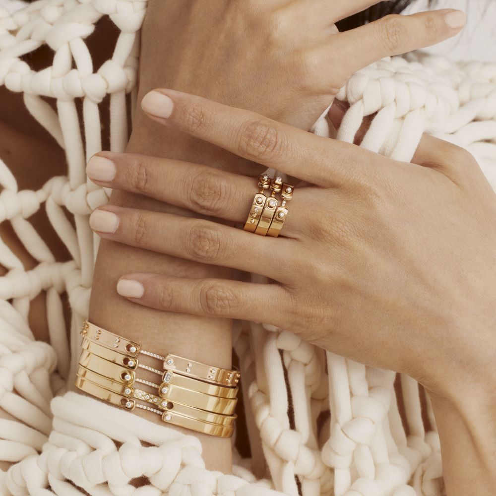 A woman wearing a Nouvel Heritage sweater and Nouvel Heritage gold rings adorned with white diamonds.