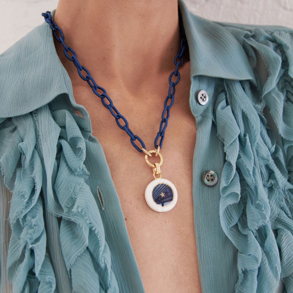 A woman wearing a blue blouse with a Silk Thread Chain Necklace by Anna Maccieri Rossi featuring charms.