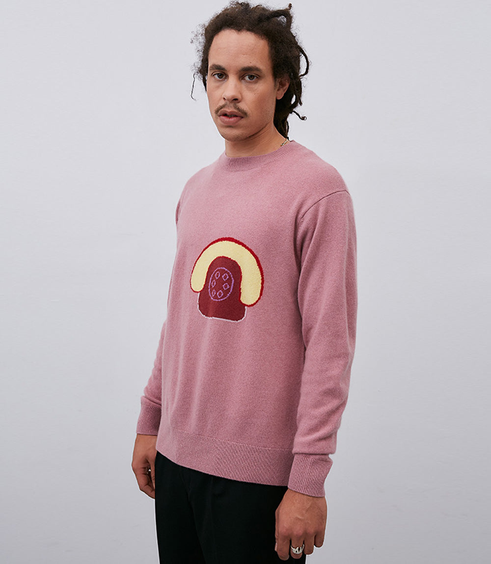 A man wearing a pink Leret Leret No. 53 Phone Sweater with ribbed cuffs.
