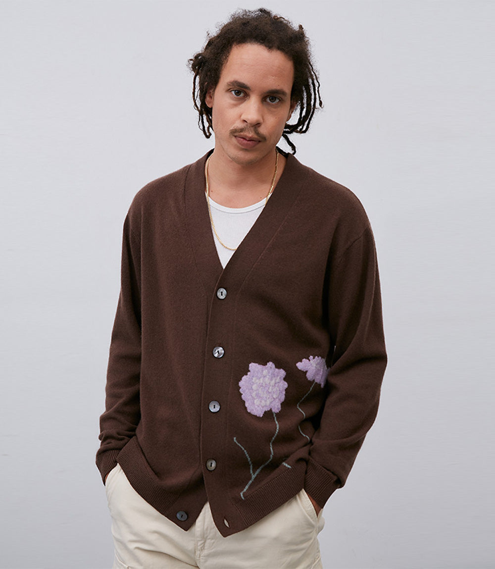 A man wearing a Leret Leret No. 54 Flower Cardigan with purple flowers on it.