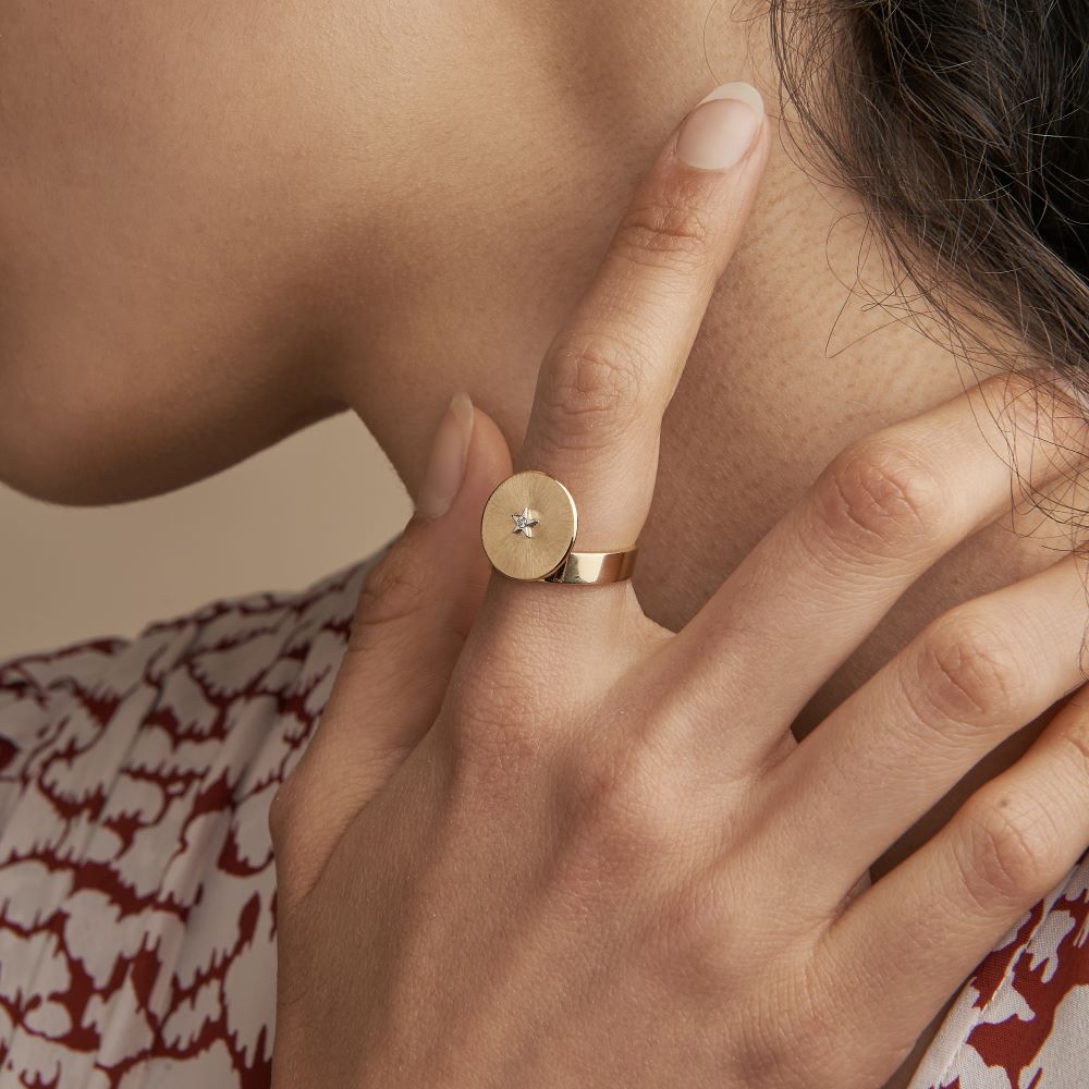 A woman wearing an Anna Maccieri Rossi Gold Mini Adjustable Signet Ring adorned with a diamond.