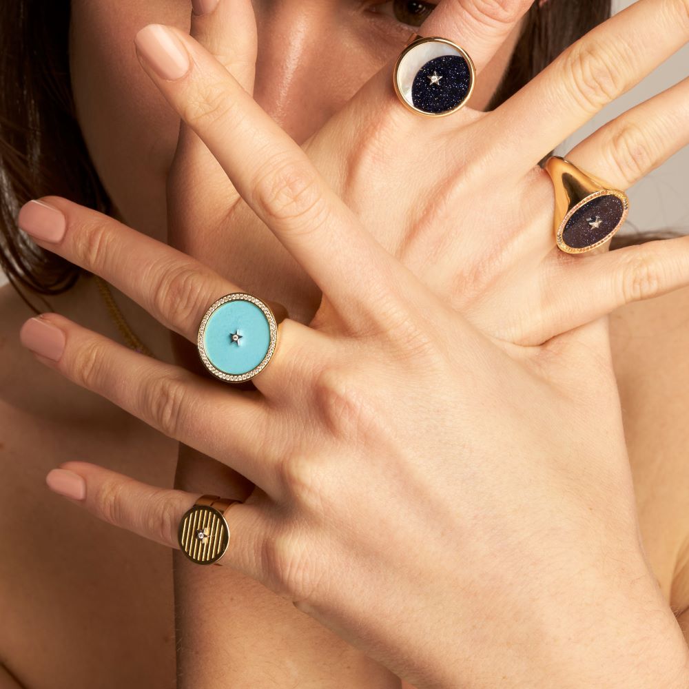 A woman wearing a Striped Gold Adjustable Ring with a blue stone by Anna Maccieri Rossi.