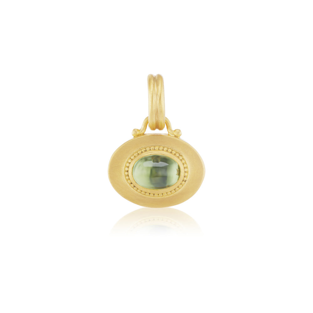 A yellow gold pendant with a Prounis Granulated Heart Charm and green stone and sapphire charm.