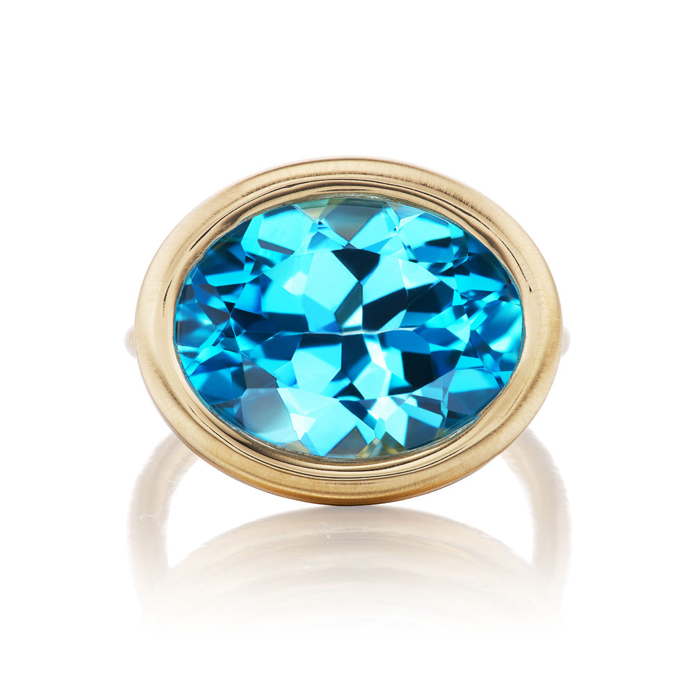A stunning Scuba Ring by Beck featuring an oval blue topaz set elegantly in lustrous yellow gold.