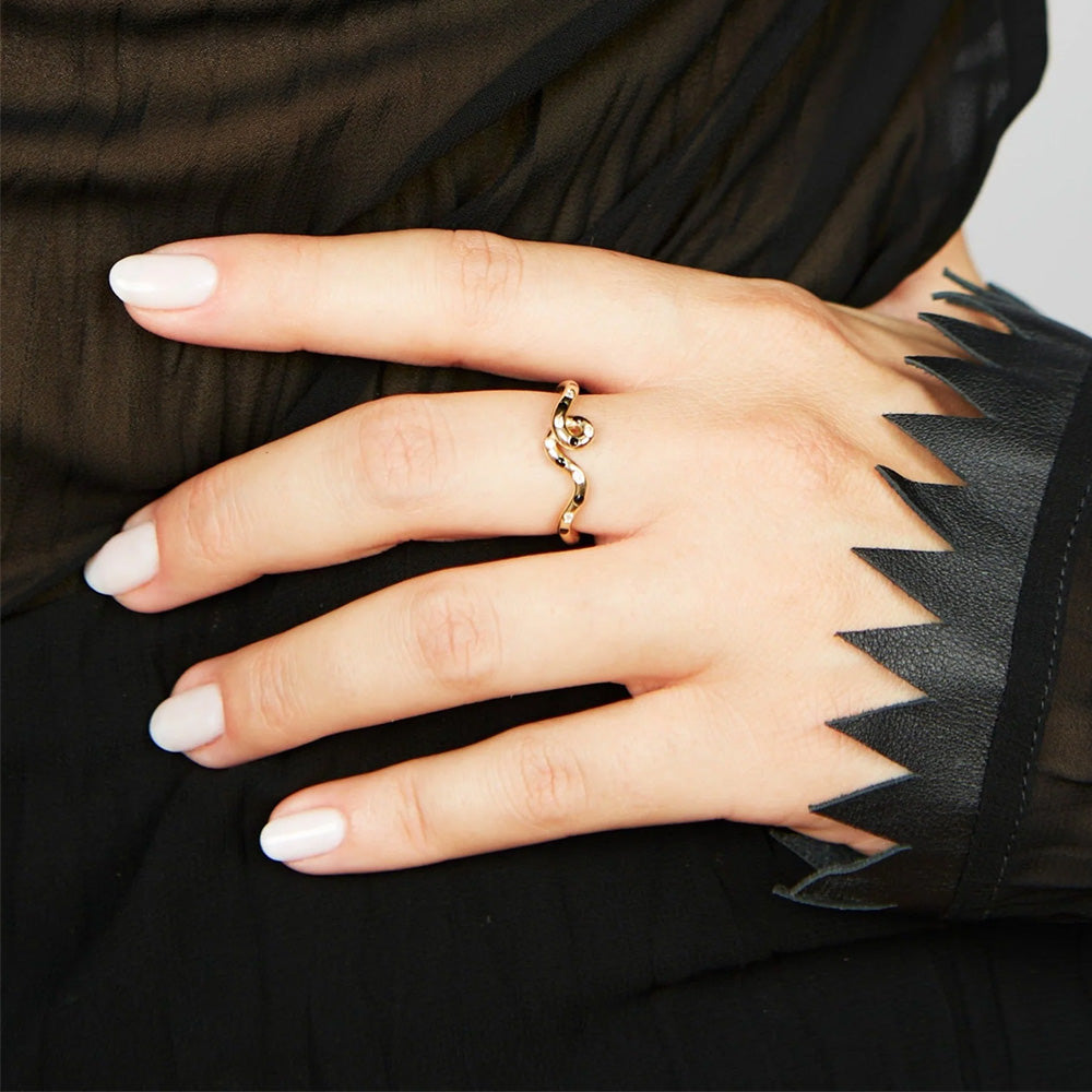 A woman's hand holding a Bea Bongiasca Wave Ring.